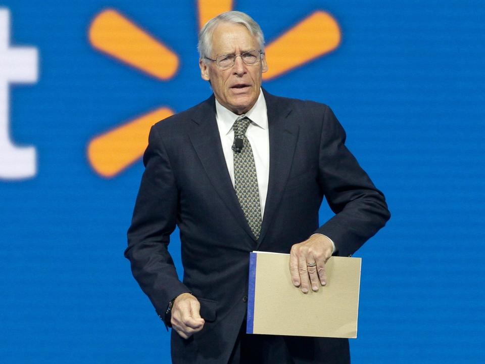 Rob Walton holds notepad standing in front of Walmart logo onstage