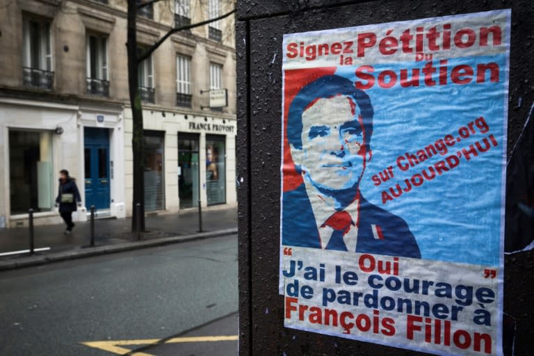 A woman passes a poster for a petition in support of French presidential election candidate for the right-wing Les Republicains party Francois Fillon on March 6, 2017 in Paris