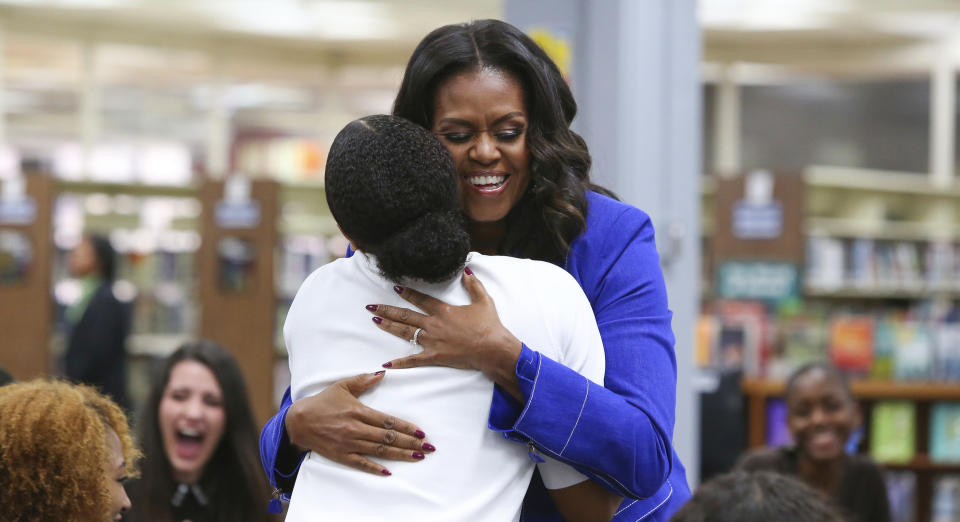 Former first lady Michelle Obama embraces a student at her alma mater, Whitney M. Young Magnet High School, on Chicago's West Side, Monday, Nov. 12, 2018, a day before the launch of a book tour to promote her memoir, "Becoming." (AP Photo/Teresa Crawford)