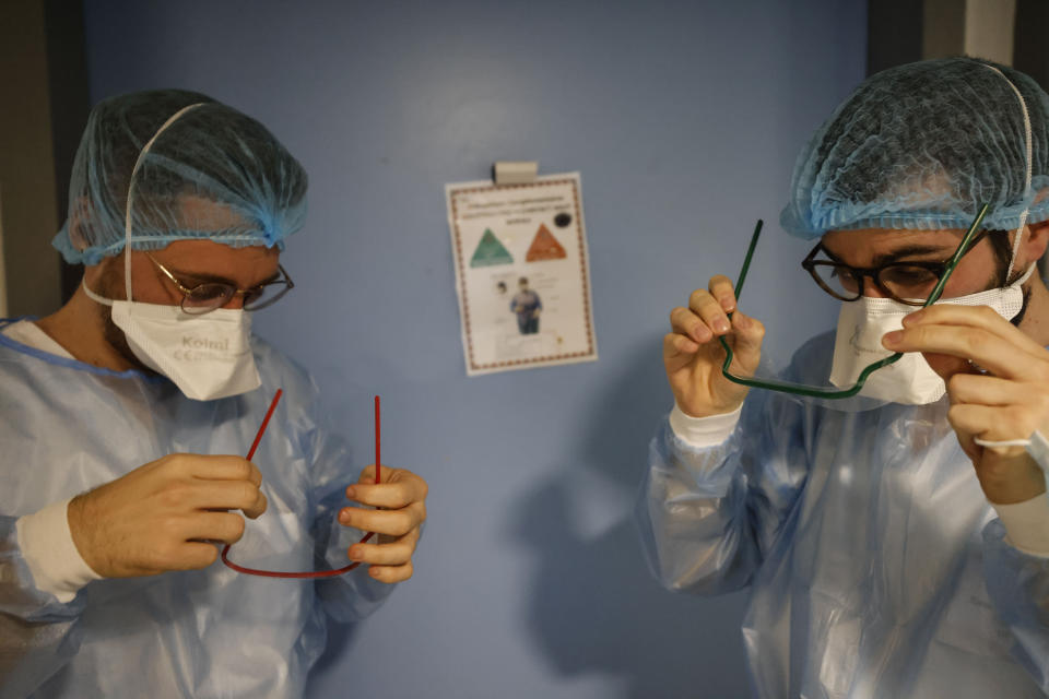 Medical staff members adjust their protective glasses in the infectious disease ward of the Strasbourg University Hospital, eastern France, Thursday Jan. 13, 2022. The omicron variant is exposing weaknesses at the heart of Europe's public health system. In France and Britain, a sharp rise in coronavirus hospitalizations coupled with staff falling sick has led to a shortage of beds. (AP Photo/Jean-Francois Badias)