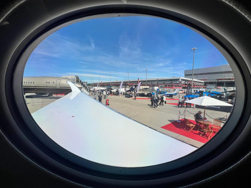 A panoramic window on a Gulfstream G700 shows the wing and a view of EBACE