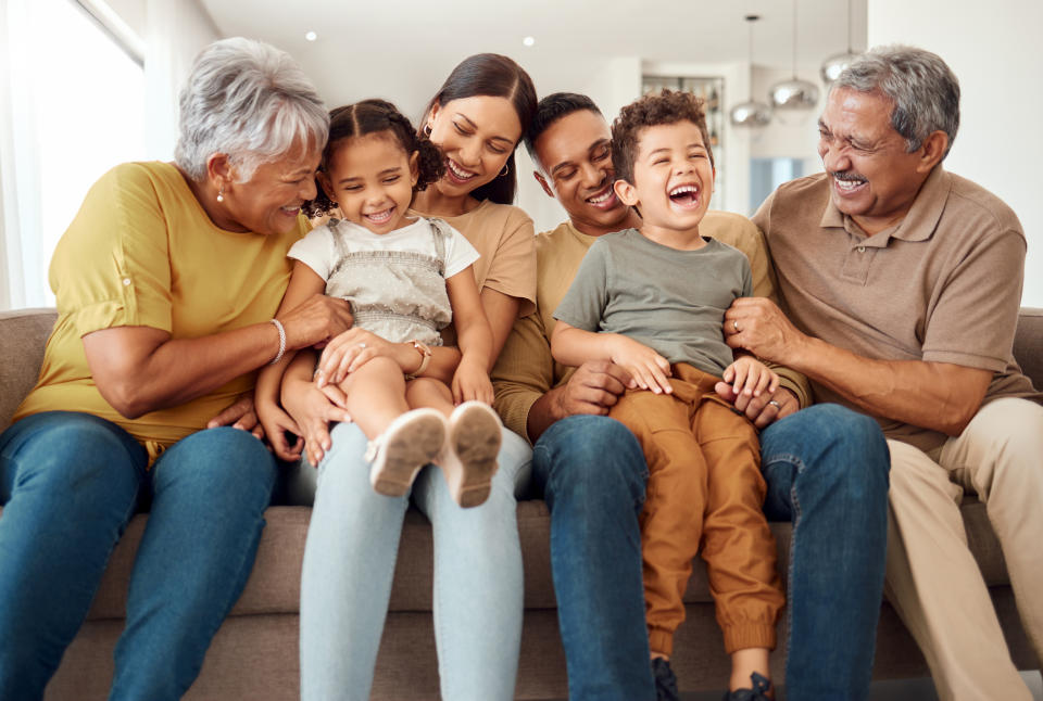 Family with grandparents and children sitting together on a couch, smiling and hugging