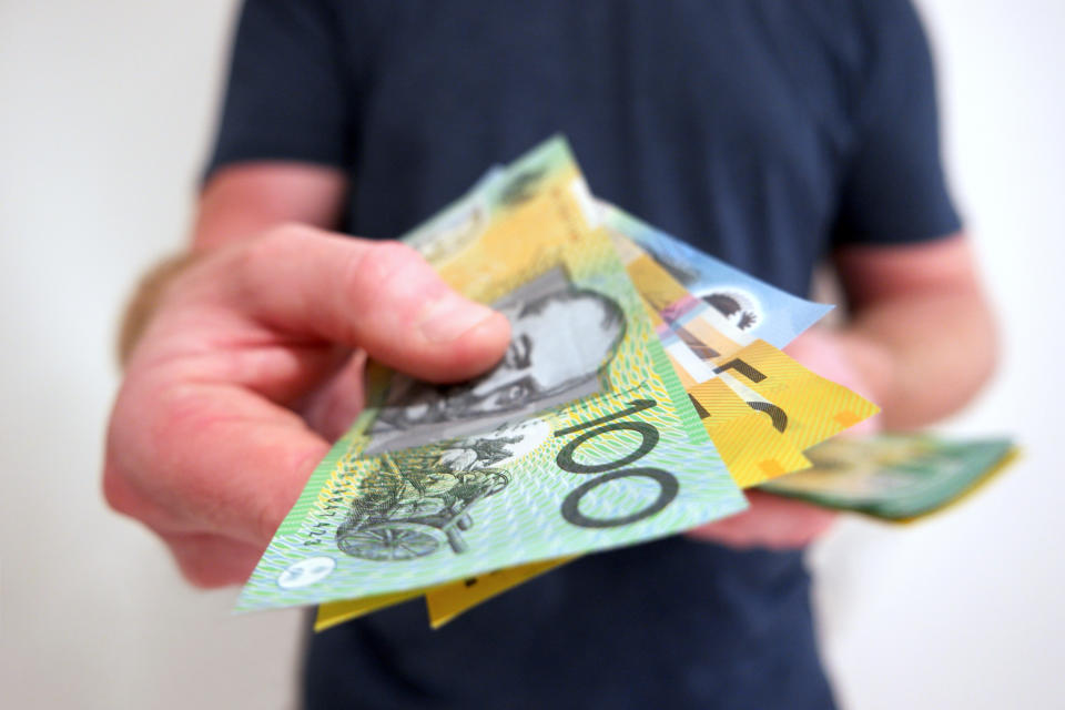 A man handing out Australian dollar bills.