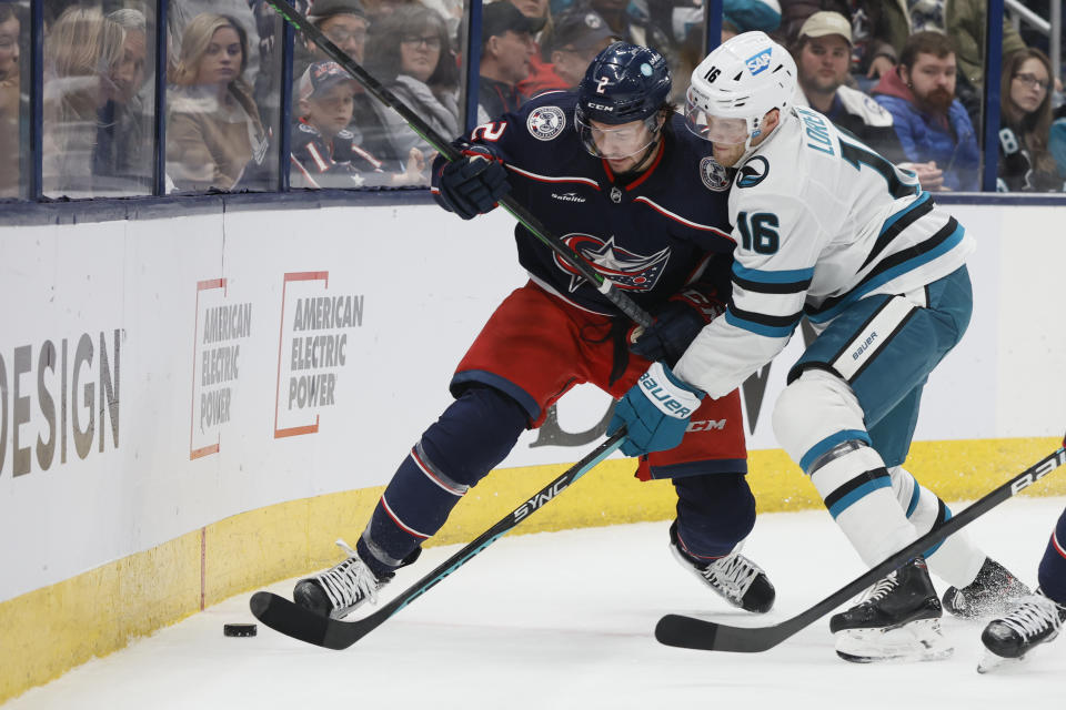Columbus Blue Jackets' Andrew Peeke, left, and San Jose Sharks' Steven Lorentz fight for a loose puck during the first period of an NHL hockey game on Saturday, Jan. 21, 2023, in Columbus, Ohio. (AP Photo/Jay LaPrete)