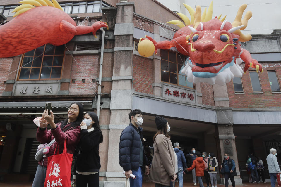 People walk under dragon balloons decorated on a building for the upcoming Lunar New Year celebrations at the Dihua street market in Taipei, Taiwan, Thursday, Feb. 8, 2024. Taiwanese shoppers started hunting for delicacies, dried goods and other bargains at the market ahead of the Lunar New Year celebrations which fall on Feb. 10 this year. (AP Photo/Chiang Ying-ying)