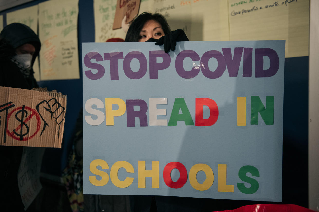 A New York City public school teacher holds a sign at a rally demanding increased COVID-19 safety measures and a remote learning option.