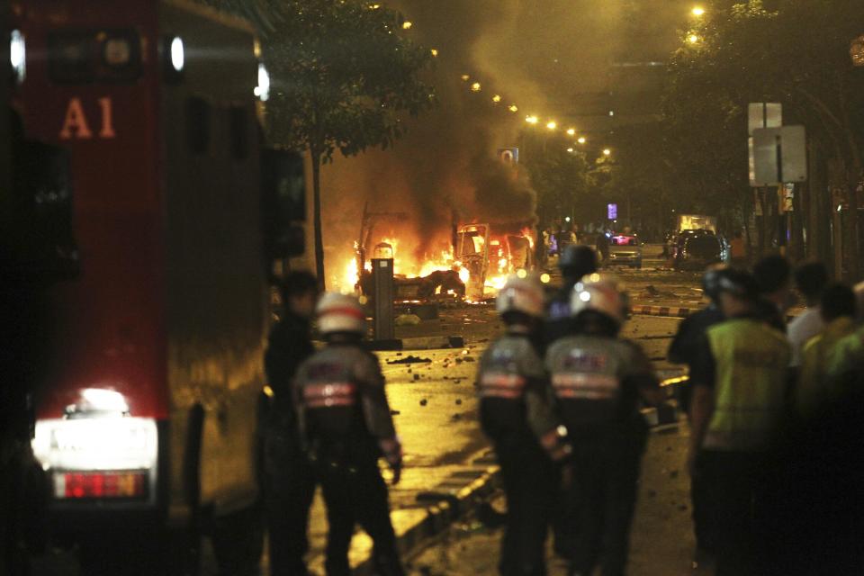 Riot policemen watch burning vehicles during a riot in Singapore's Little India district, late December 8, 2013. A crowd set fire to vehicles and clashed with police in the Indian district of Singapore late on Sunday, in a rare outbreak of rioting in the city state. Television footage showed a crowd of people smashing the windscreen of a bus, and at least three police cars being flipped over. The Singapore Police Force said the riot started after a fatal traffic accident in the Little India area. REUTERS/Dennis Thong/Lianhe Zaobao (SINGAPORE - Tags: CIVIL UNREST TPX IMAGES OF THE DAY) ATTENTION EDITORS - THIS IMAGE HAS BEEN SUPPLIED BY A THIRD PARTY. IT IS DISTRIBUTED, EXACTLY AS RECEIVED BY REUTERS, AS A SERVICE TO CLIENTS. NO SALES. NO ARCHIVES. FOR EDITORIAL USE ONLY. NOT FOR SALE FOR MARKETING OR ADVERTISING CAMPAIGNS. SINGAPORE OUT. NO COMMERCIAL OR EDITORIAL SALES IN SINGAPORE