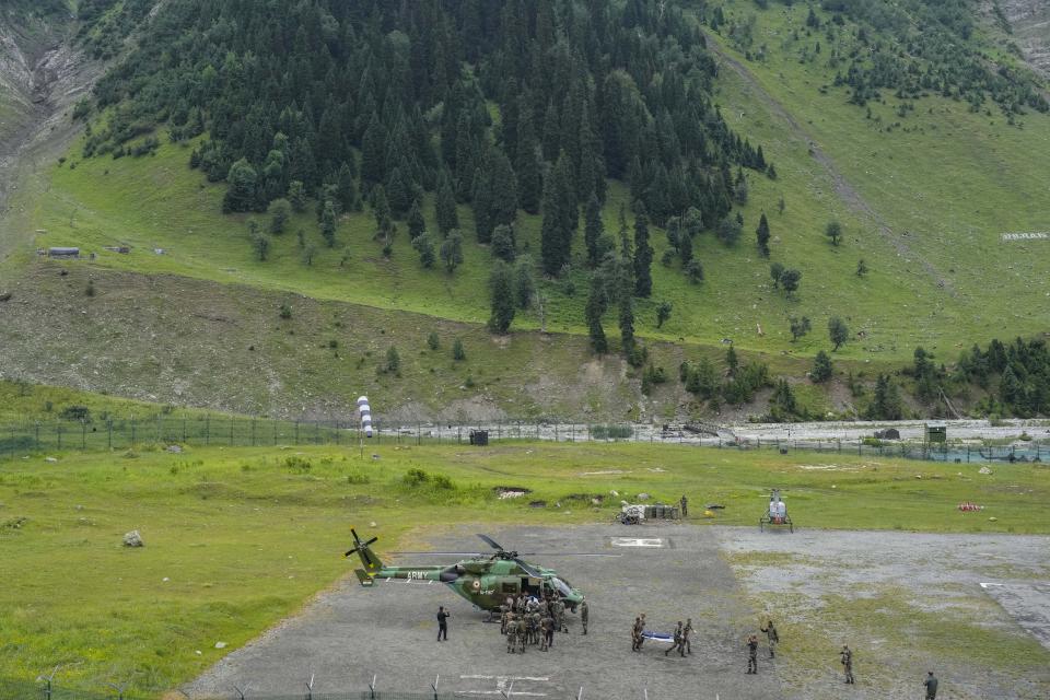 Indian army soldiers carry an injured of a cloudburst for treatment, at Baltal, 105 kilometers (65miles) northeast of Srinagar, Indian controlled Kashmir, Saturday, July 9, 2022. At least eight pilgrims have been killed after a cloudburst triggered a flash flooding during an annual Hindu pilgrimage to an icy Himalayan cave in Indian-controlled Kashmir. Officials say the cloudburst near the hollowed mountain cave revered by Hindus on Friday sent a wall of water down a mountain gorge and swept about two dozen encampments and two makeshift kitchens. (AP Photo/Mukhtar Khan)