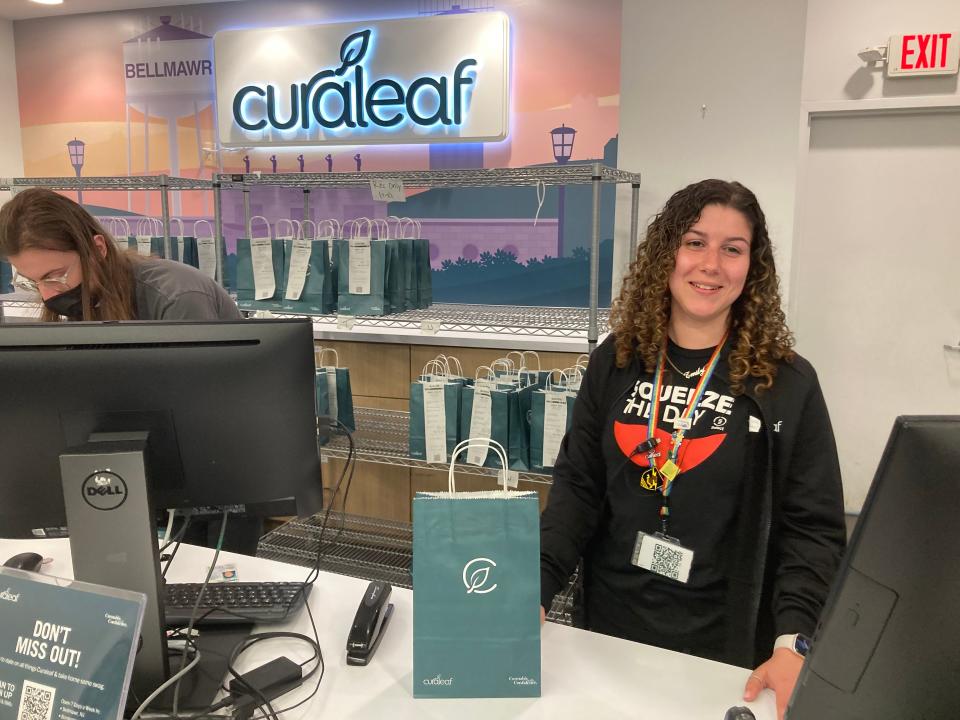 Emily, a budtender at Curaleaf, behind the checkout counter on a busy Thursday morning. The staff were friendly and helpful, but no last names were allowed. The bags of cannibis products on the rack behind her. Curaleaf clients must order online prior to stepping into the store, and the staff retrieves the goods and bags it.