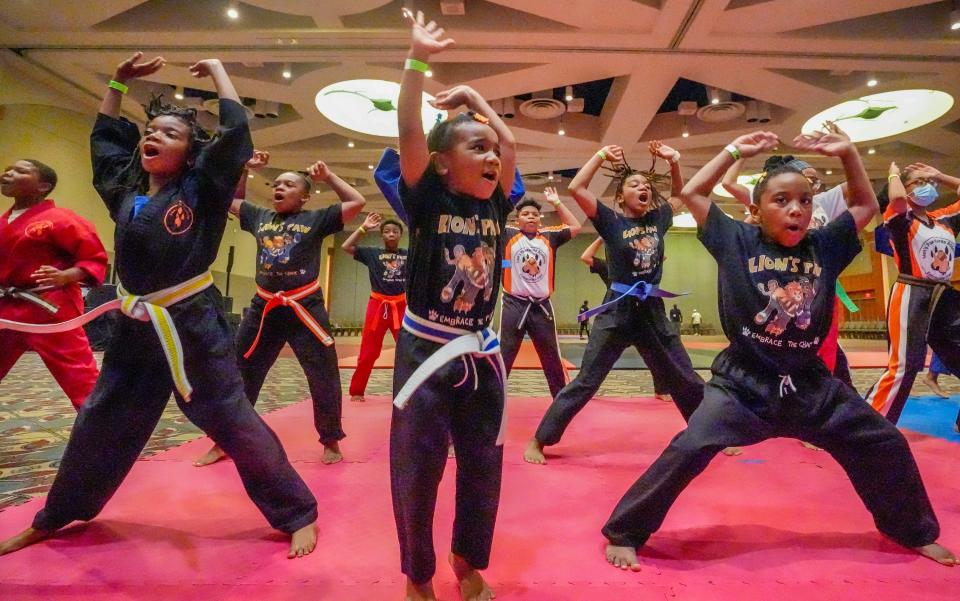 Kyra Beckley, 3, middle, does jumping jacks prior to the martial arts and self-defense training for youth at the Wisconsin Center in Milwaukee.