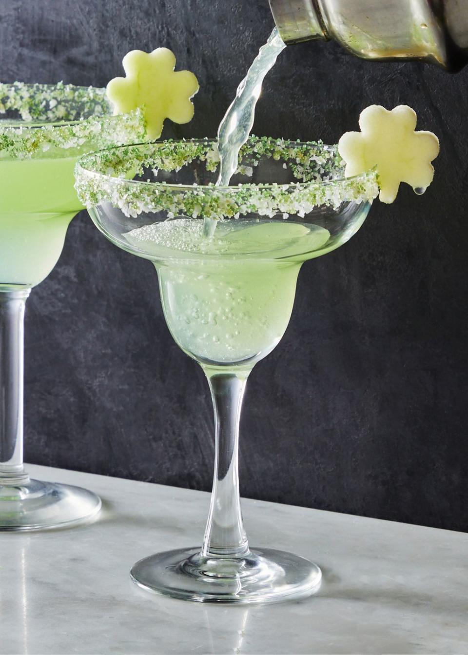 light green shamrockarita cocktail in a sugar rimmed glass with an apple slice shaped like a shamrock as garnish