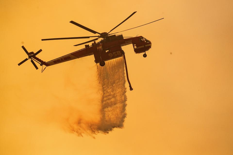 A helicopter drops water on a burning hillside during the Mendocino Complex Fire near Finley, California.