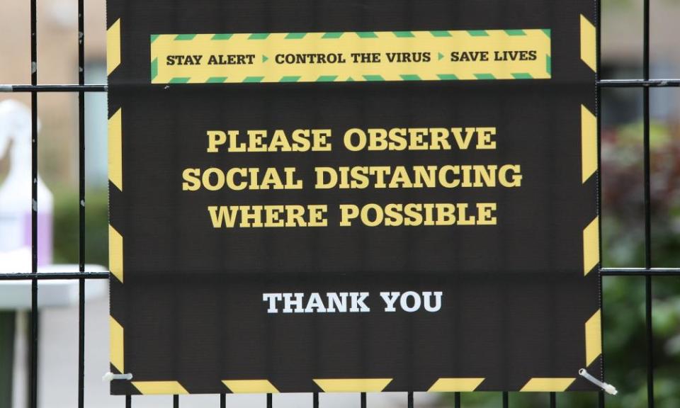 A physical-distancing sign on the gate of a campus.