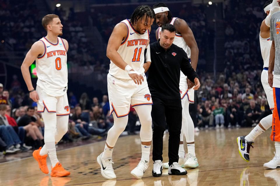 New York Knicks guard Jalen Brunson (11) is helped off the court after an injury in the first half of an NBA basketball game against the Cleveland Cavaliers, Sunday, March 3, 2024, in Cleveland. (AP Photo/Sue Ogrocki)