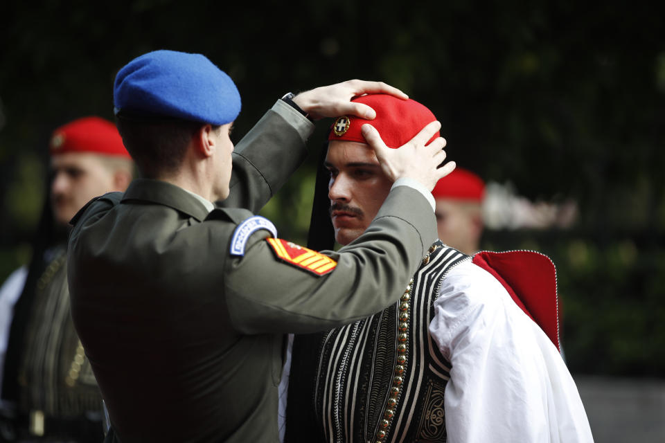 An officer adjust the attire of an Evzone, Greek Presidential guard, prior to a welcome ceremony for China's President Xi Jinping, outside the Presidential palace in Athens, Monday, Nov. 11, 2019. Xi Jinping is in Greece on a two-day official visit. (AP Photos/Thanassis Stavrakis)