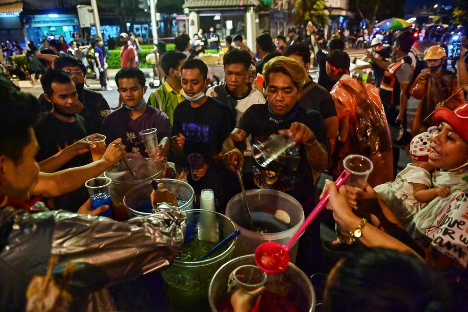 Pro-democracy protesters pause to grab drinks from a street vendor in Bangkok on Wednesday  (AFP via Getty Images)