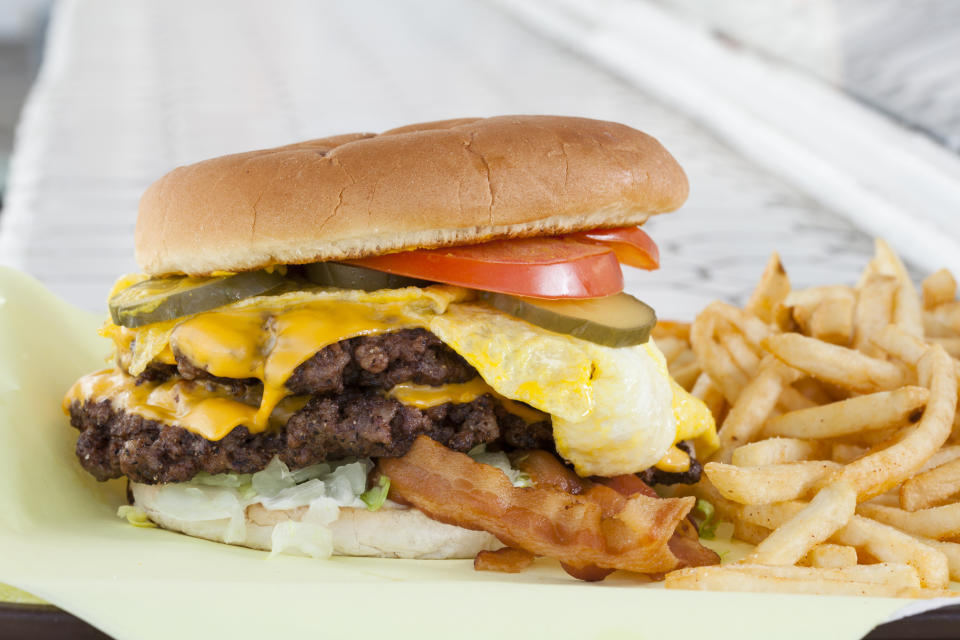 Cheeseburger with bacon, egg, vegetables, and fries on the side, served on a tray