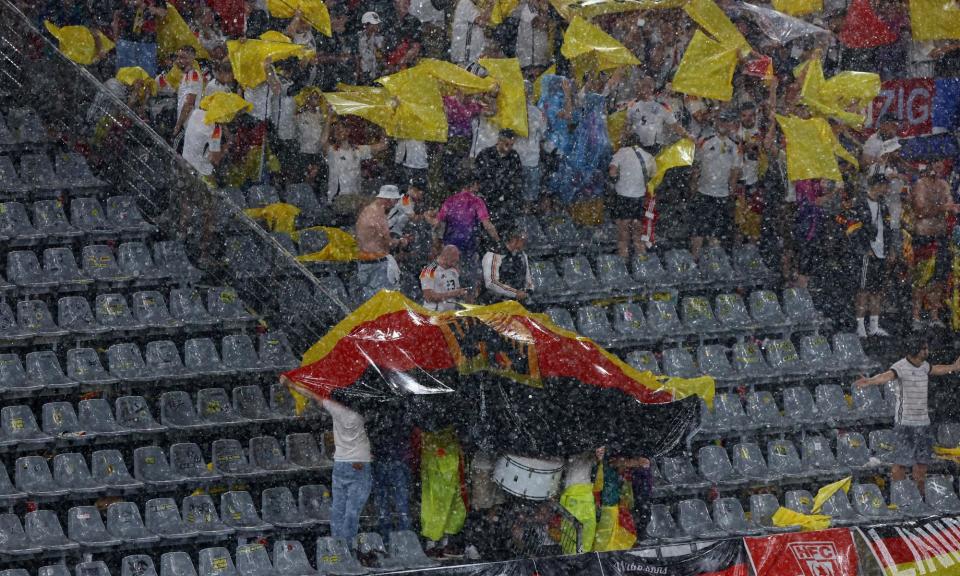 <span>Germany fans shelter from the rain after the last-16 game in <a class="link " href="https://sports.yahoo.com/soccer/teams/dortmund/" data-i13n="sec:content-canvas;subsec:anchor_text;elm:context_link" data-ylk="slk:Dortmund;sec:content-canvas;subsec:anchor_text;elm:context_link;itc:0">Dortmund</a> is stopped because of adverse weather conditions.</span><span>Photograph: Bernadett Szabó/Reuters</span>