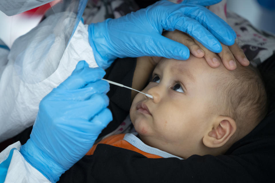 A doctor collects a sample for a coronavirus test from a bsby in Subang on the outskirts of Kuala Lumpur, Malaysia, on Thursday, Oct. 29, 2020. Malaysia extended restricted movements in its biggest city Kuala Lumpur, neighboring Selangor state and the administrative capital of Putrajaya from Wednesday in an attempt to curb a sharp rise in coronavirus cases. (AP Photo/Vincent Thian)