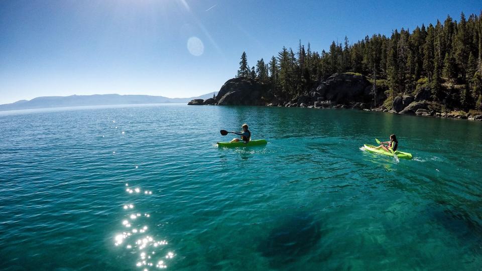 Children kayak and play in the beautiful clear waters of Lake Tahoe, California on a beautiful summer morning.