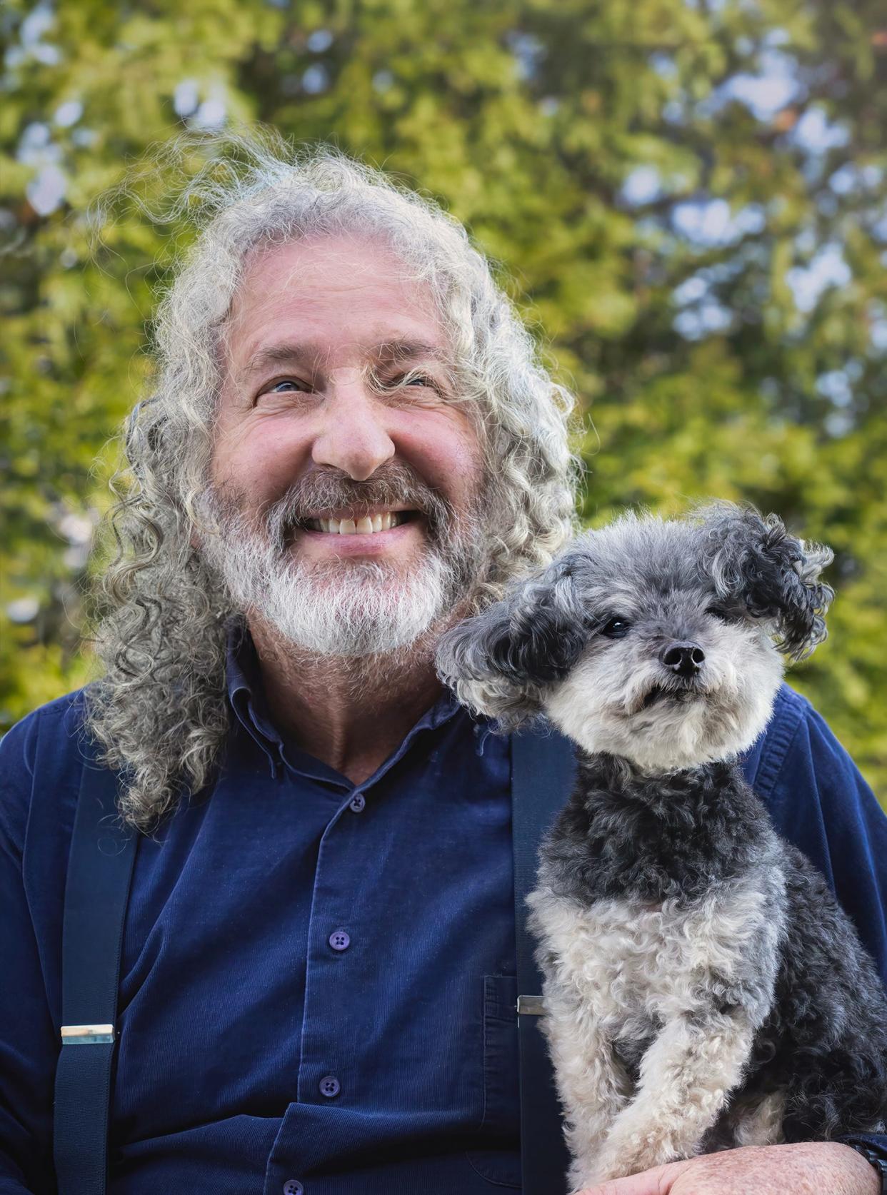 A dog poses with its owner. Both appear to have beards.