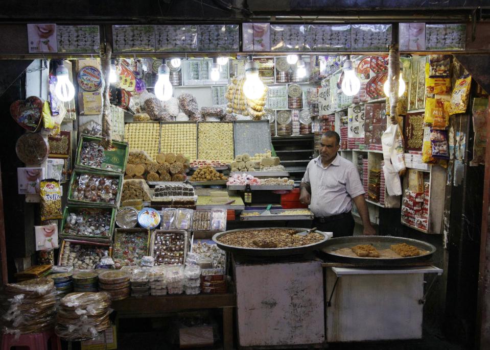 In this photo taken in Tuesday, Oct. 30, 2012, shop staff wait for customers in Najaf, Iraq. The plunge in Iran's currency is proving bad for business in neighboring Iraq. Fewer Iranians are now able to afford visits to Shiite holy sites here and elsewhere in Iraq because each dollar or Iraqi dinar now costs roughly three times what it did as recently as last year. That has pushed the price of organized tours up sharply and made Iraqi merchants far less willing to accept rials as payment. (AP Photo/Khalid Mohammed)