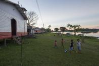 Children of the Sao Raimundo do Jaraua community play soccer along the edge of a tributary of the Solimoes river, one of the main tributaries of the Amazon, where adults fish for arapaima or pirarucu, the largest freshwater fish species in South America and one of the largest in the world, in the Mamiraua nature reserve near Fonte Boa about 600 km (373 miles) west of Manaus, November 27, 2013. Catching the arapaima, a fish that is sought after for its meat and is considered by biologists to be a living fossil, is only allowed once a year by Brazil's environmental protection agency. The minimum size allowed for a fisherman to keep an arapaima is 1.5 meters (4.9 feet). Picture taken November 27, 2013. REUTERS/Bruno Kelly (BRAZIL - Tags: ENVIRONMENT SOCIETY ANIMALS) ATTENTION EDITORS: PICTURE 03 OF 22 FOR PACKAGE 'FISHING FOR BRAZIL'S FOSSILS'. TO FIND ALL IMAGES SEARCH 'ARAPAIMA KELLY'