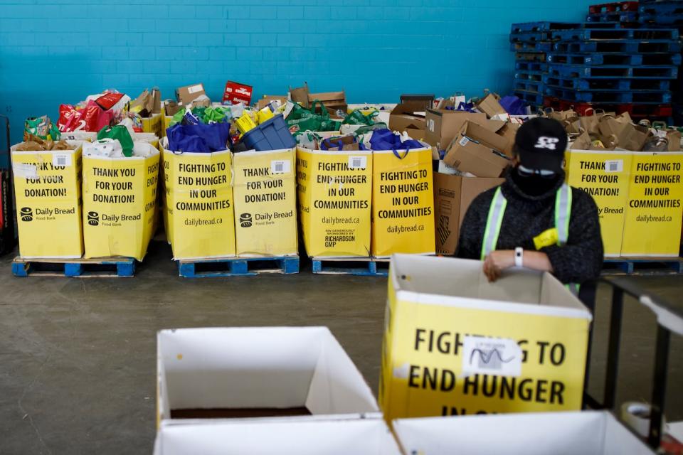 A volunteer organizes boxes for food at the Daily Bread Food Bank's Spring Drive-Thru food drive at the food bank in Etobicoke, Ontario on Saturday, April 3, 2021. In the past six months, the Daily Bread Food Bank and its member agencies have seen an average of 105,000 client visits each month, a 51 per cent increase compared to previous year. 