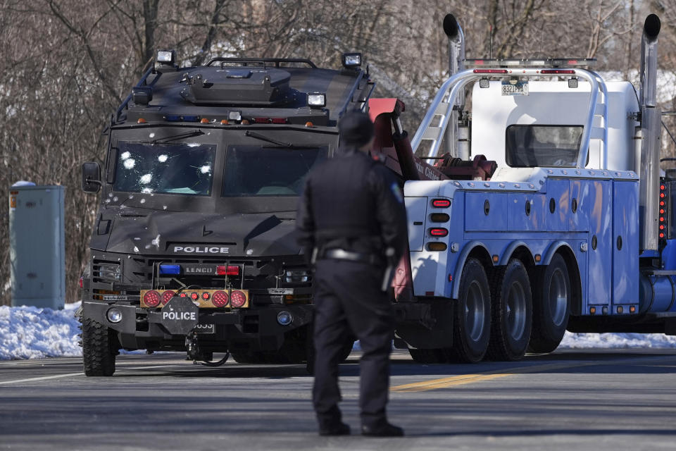 FILE - A police vehicle with what appears to be bullet pockmarks is towed near the scene where two police officers and a first responder were shot and killed, Feb. 18, 2024, in Burnsville, Minn. A woman has been charged with illegally buying guns used in the killings of the three Minnesota first responders in a standoff at a home in Burnsville, where seven children were inside, U.S. Attorney Andrew M. Luger announced Thursday, March 14, at a news conference. (AP Photo/Abbie Parr, File)