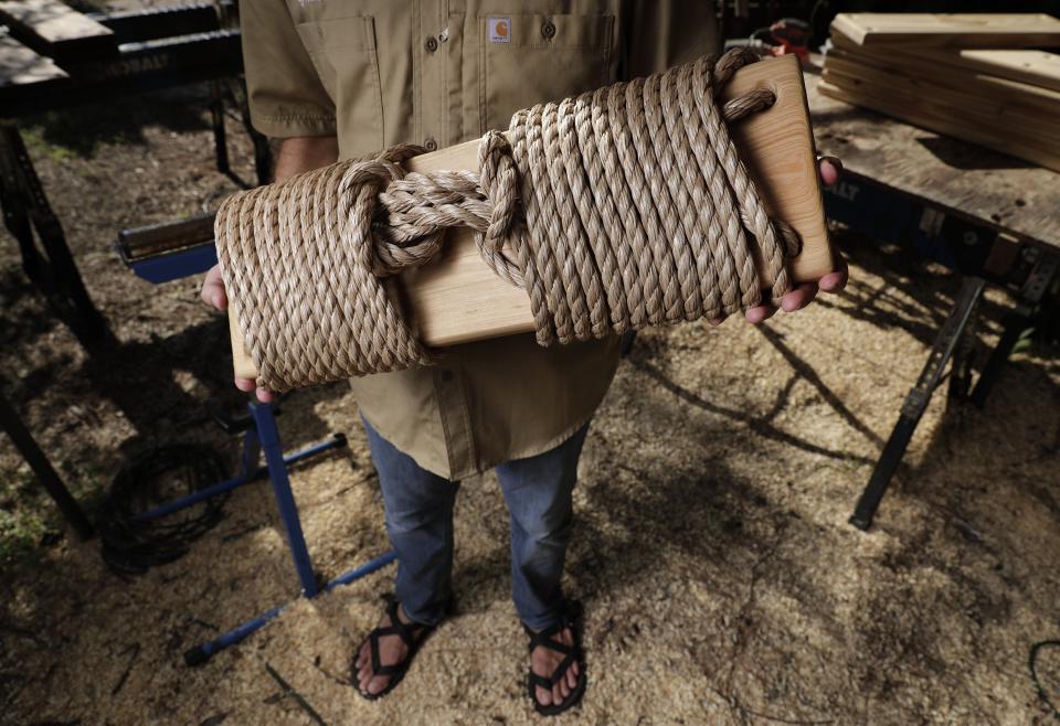 Zac West holds one of his cypress swings. Part of the proceeds of each swing goes to a reforestation program in Tanzania, where he used to live, and the rope in each swing is braided by clients of Beyond 90, a nonprofit that aids refugees in Northeast Floria.