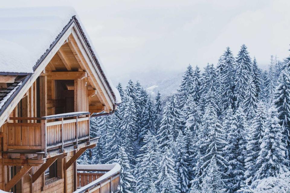 A wooden cabin house in the snow winter mountain setting of pine trees
