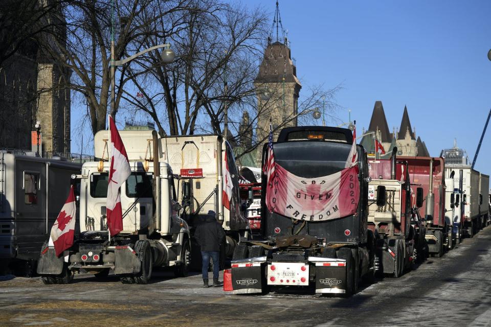 A person walks among trucks on Wellington Street on the 18th day of the so-called freedom convoy protest in Ottawa in February 2022. THE CANADIAN PRESS/Justin Tang