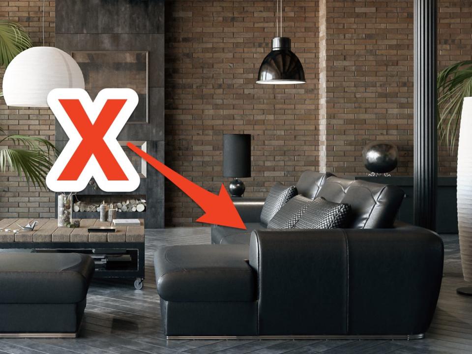 red x and arrow pointing at a low black couch in an industrial style living room