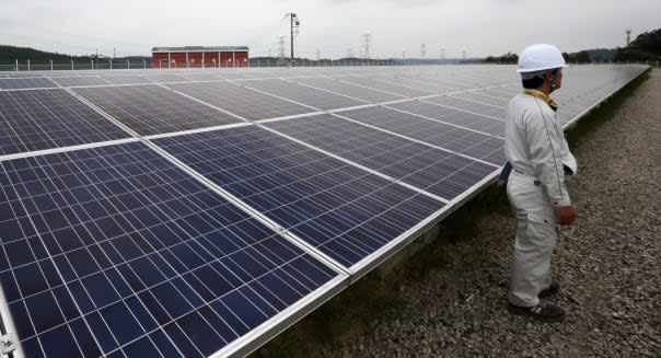 A worker stands near solar panels, manufactured by Sharp Corp., at the SoftBank Yaita Solar Park operated by SB Energy Corp. in Yaita City, Tochigi Prefecture, Japan, on Tuesday, Aug. 20, 2013. The 3 megawatt solar power station is scheduled to start operations from Aug. 23. Photographer: Tomohiro Ohsumi/Bloomberg via Getty Images