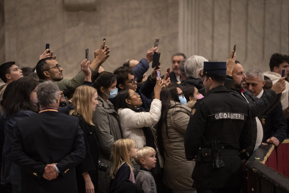 Mourners take photographs of the body of Pope Emeritus Benedict XVI as it lies in state inside St. Peter's Basilica at The Vatican where thousands went to pay their homage Monday, Jan. 2, 2023. The Vatican announced that Pope Benedict died on Dec. 31, 2022, aged 95, and his funeral will be held Thursday, Jan. 5, 2023. (AP Photo/Ben Curtis)