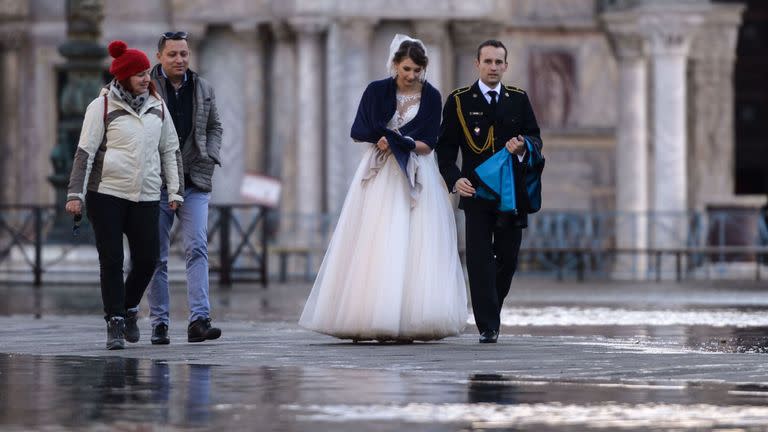 A newlywed couple walk across a flooded square in the lagoon city