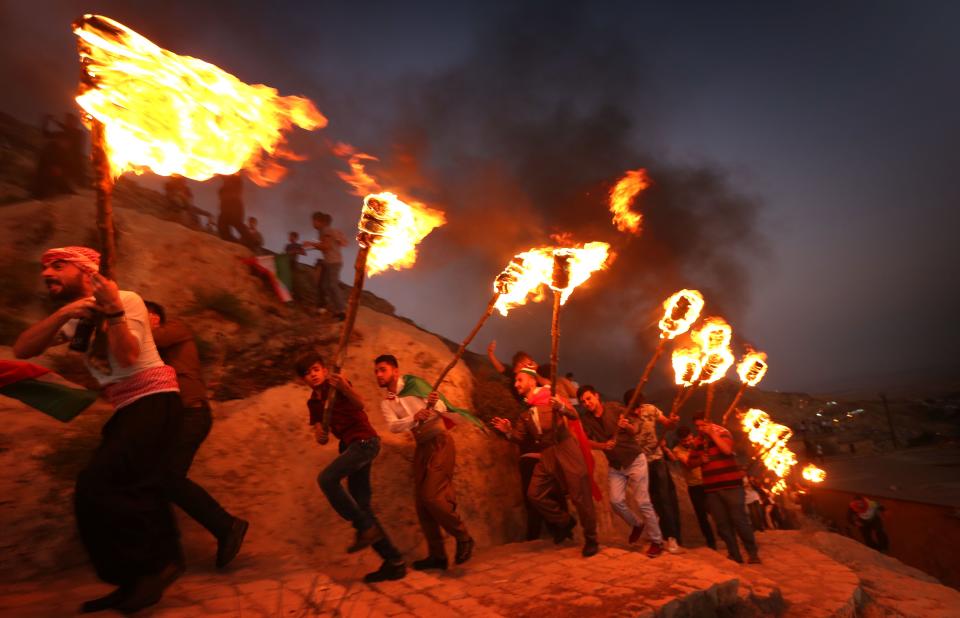 <p>Iraqi Kurds wave Kurdish flags and hold torches as they walk up a mountain during a gathering to show support for the upcoming independence referendum and encourage people to vote in the town of Akra, some 300 miles north of Baghdad, Sept. 10, 2017. (Photo: Safin Hamed/AFP/Getty Images) </p>