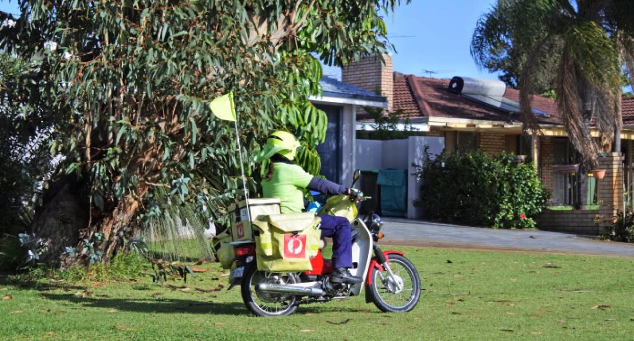 Australia Post postie on bike on grass