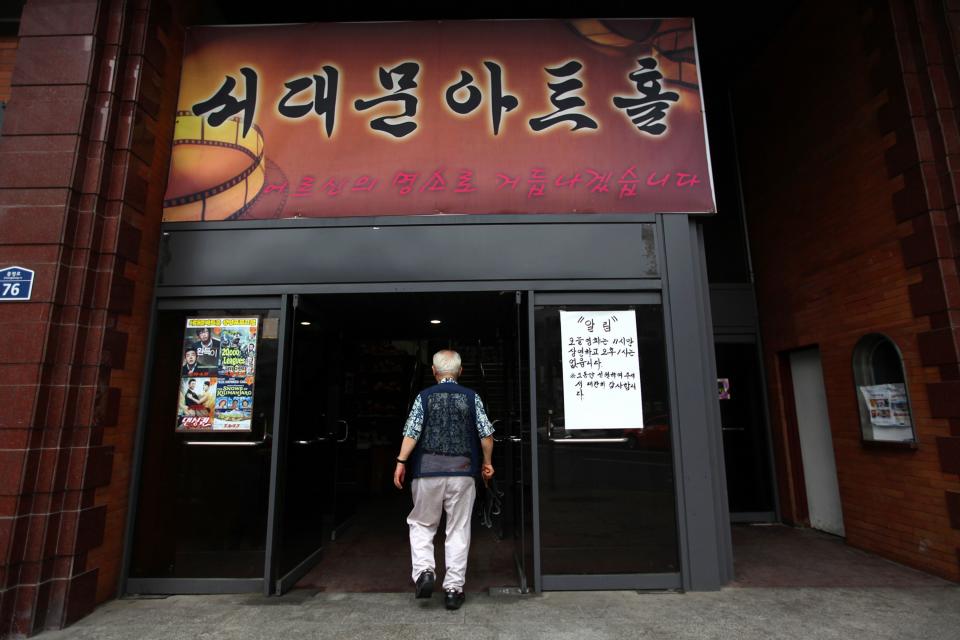 A senior patron of Seoul's last old-style one-screen cinema steps inside for the theater's last screening at Seodaemun Art Hall in Seoul, South Korea, Wednesday, July 11, 2012. Seoul's last old-style one-screen cinema, soon to be knocked down and replaced by a new tourist hotel, played its final movie Wednesday - the Italian classic "The Bicycle Thief." The letters at a banner read " Seodaemun Art Hall". (AP Photo/Hye Soo Nah)