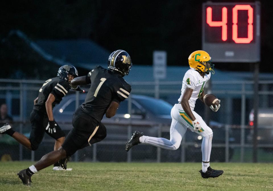Jayvion Showers (4) slips past the Milton defenders on his way to a touchdown and a 6-0 Crusaders lead during the Pensacola Catholic vs Milton football game at Milton High School on Thursday, Sept. 1, 2022.