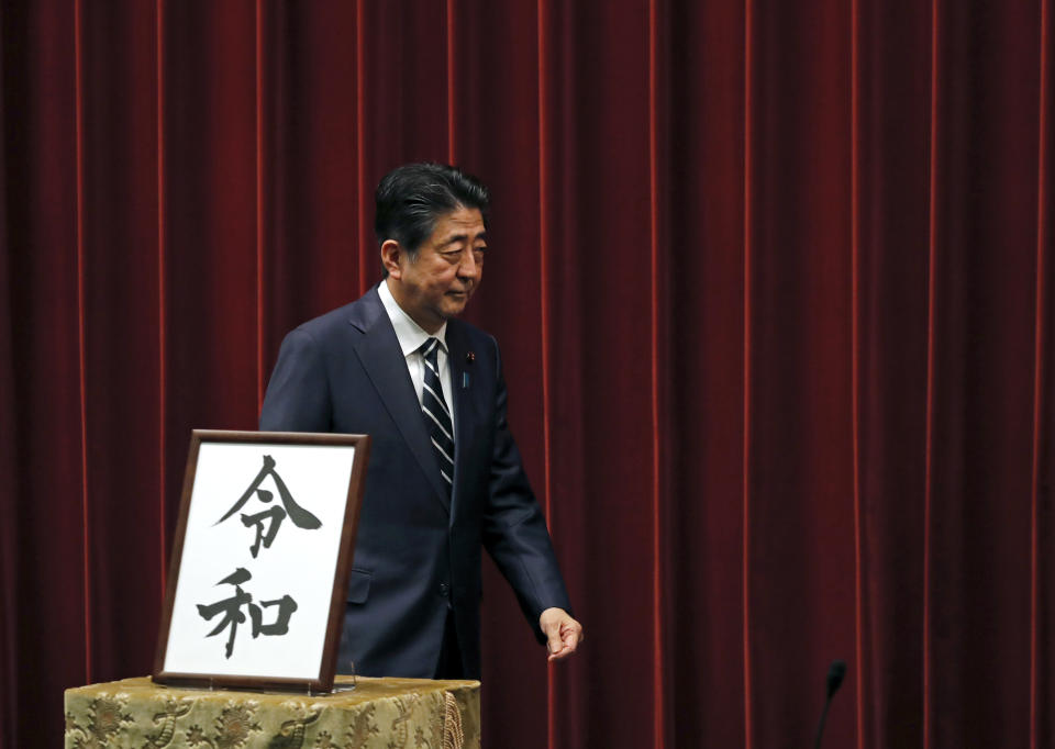 Japanese Prime Minister Shinzo Abe walks past the name of new era "Reiwa" on display at the Prime Minister's office in Tokyo, Monday, April 1, 2019. Japan says next emperor Naruhito’s era name is Reiwa, effective May 1 when he takes the throne from his father.(AP Photo/Eugene Hoshiko)