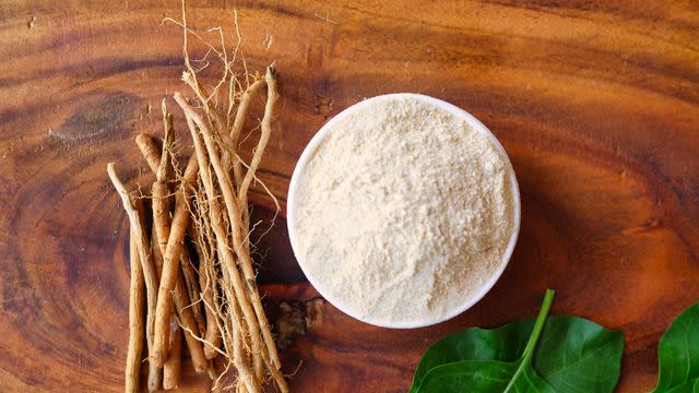 <p>Azay photography / Getty Images</p> Ashwagandha (Withania somnifera) roots and powder in white bowl on wooden background.