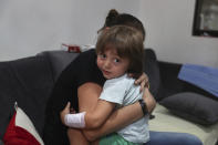 CORRECTS THE FAMILY NAME OF THE BOY - Hiba Achi hugs her son, three-year-old Abed Itani, at her house in Beirut, Lebanon, Tuesday, Aug. 11, 2020. Abed was playing with his Lego blocks when the huge blast ripped through Beirut, shattering the nearby glass doors. He had cuts on his tiny arms and feet, a head injury, and was taken to the emergency room, where he sat amid other bleeding people. (AP Photo/Bilal Hussein)