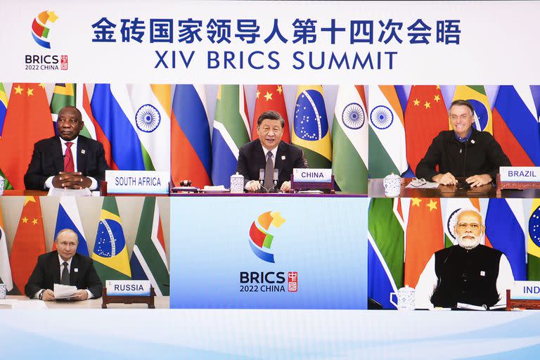 In this photo released by Xinhua News Agency, Chinese President Xi Jinping is seen on a screen with South African President Cyril Ramaphosa, Brazilian President Jair Bolsonaro, Russian President Vladimir Putin and Indian Prime Minister Narendra Modi as he hosts the 14th BRICS Summit via video link from Beijing, Thursday, June 23, 2022. Chinese President Xi Jinping opened a meeting of leaders of major developing countries on Thursday by saying the world should oppose unilateral sanctions and efforts by some countries to maintain their political and military power. (Li Tao/Xinhua via AP)