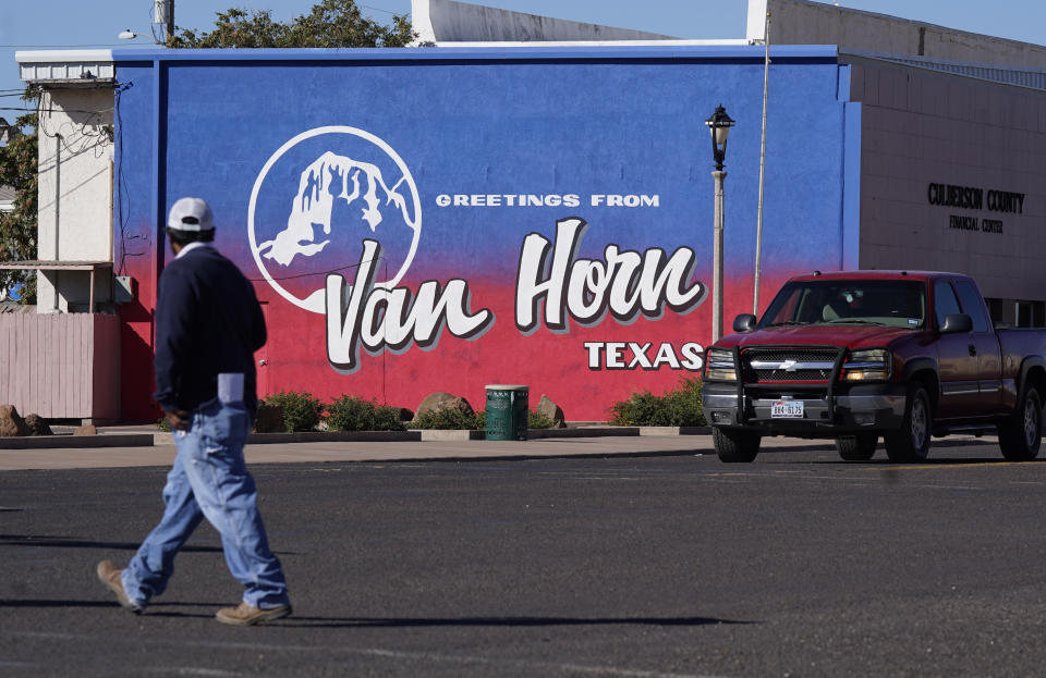 A pedestrian crosses the street in Van Horn, Texas, Monday, Oct. 11, 2021. Tuesday's Blue Origin launch near the city has been pushed to Wednesday due to weather. (AP Photo/LM Otero)