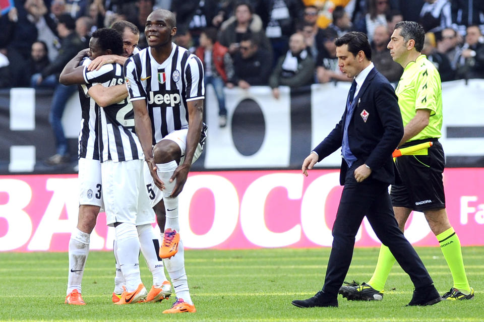 Juventus players celebrate their 1-0 win as Fiorentina coach Vincenzo Montella walks off the pitch at the end of a Serie A soccer match between Juventus and Fiorentina at the Juventus stadium, in Turin, Italy, Sunday, March 9, 2014. (AP Photo/Massimo Pinca)