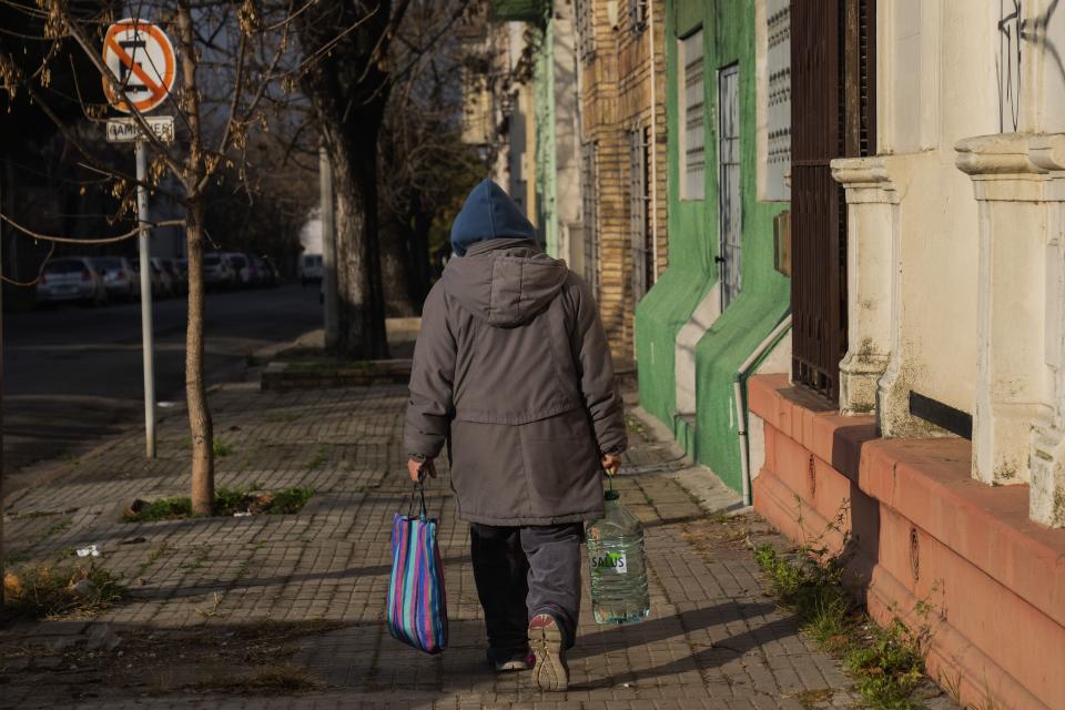 Una mujer lleva agua mineral embotellada en Montevideo, Uruguay, el miércoles 21 de junio de 2023. (AP Foto/Matilde Campodonico)