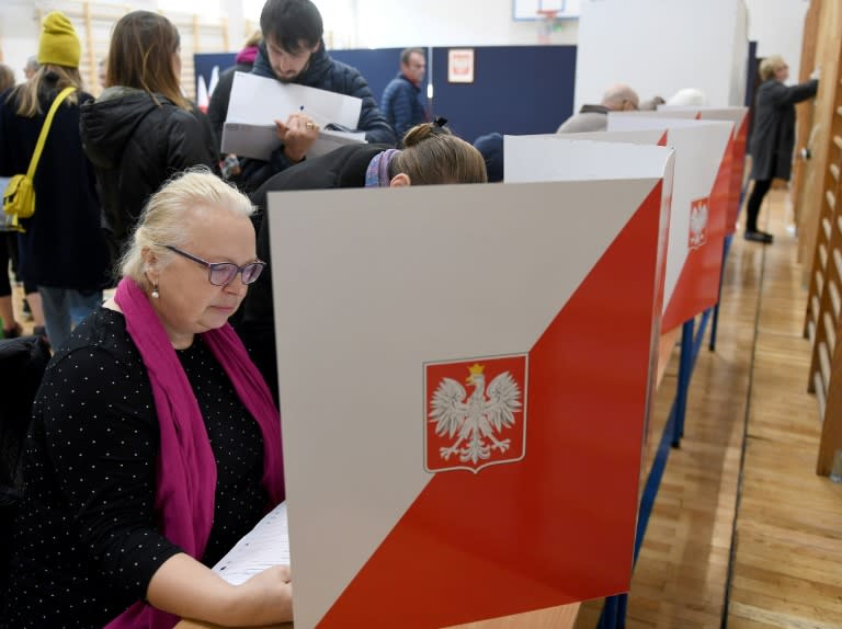 Voters check ballots at a polling station in the Polish capital Warsaw where an opposition centrist candidate has come out on top for mayor, exit polls show