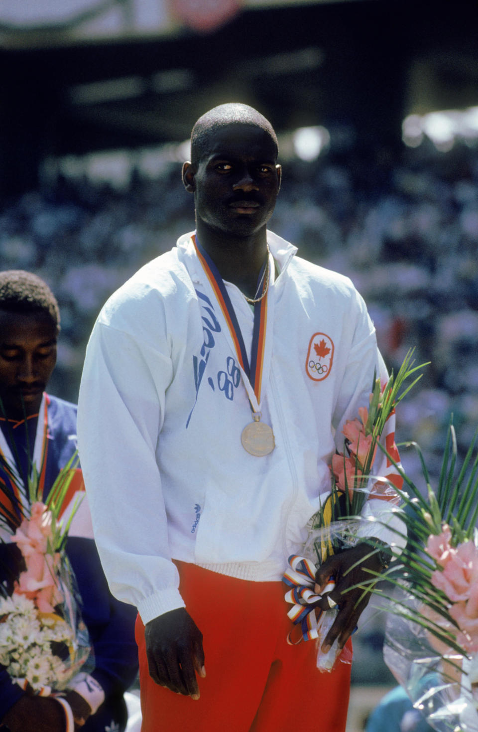 Canadian sprinter Ben Johnson on the winners podium with his gold medal after winning the 100 Metres event at Seoul Olympic Stadium during the Olympic Games in Seoul, South Korea, 24th September 1988. On the left is bronze medal winner Linford Christie of Great Britain. Johnson won the event in a world record time of 9.79 seconds, but was disqualified for doping, with Carl Lewis of the USA, taking the title. (Photo by Tony Duffy/Getty Images)