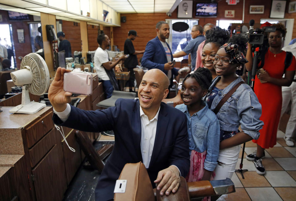 FILE - In this April 20, 2019 photo, Democratic presidential candidate Sen. Cory Booker Democratic takes a selfie with people at a barber shop during a campaign stop in Las Vegas. Booker rose to national fame as a New Jersey mayor and senator, but his mom and other relatives have lived in Las Vegas for years. Now, he’s working those local connections to set himself apart from the crowded pack in a state that could be decisive. (AP Photo/John Locher, File)